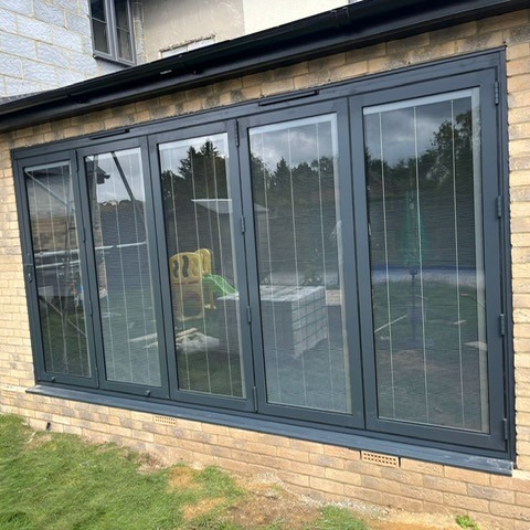 Aluminium bifold doors opening onto a garden, fitted by Andrews Glass in Hertfordshire